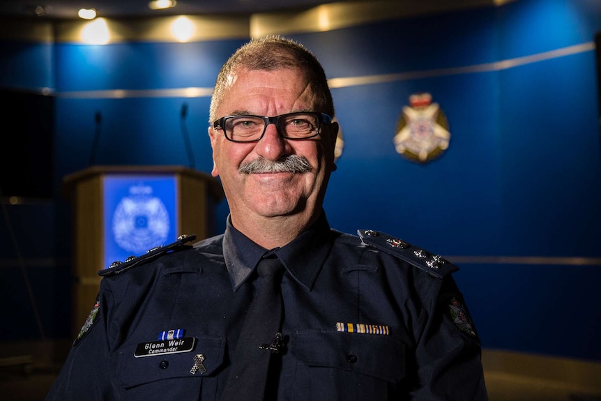 Commander Glenn Weir smiling while standing in room at Victoria Police.