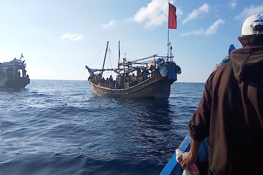 Rybacy zbliżają się do drewnianej łodzi przewożącej uchodźców z Rohingya