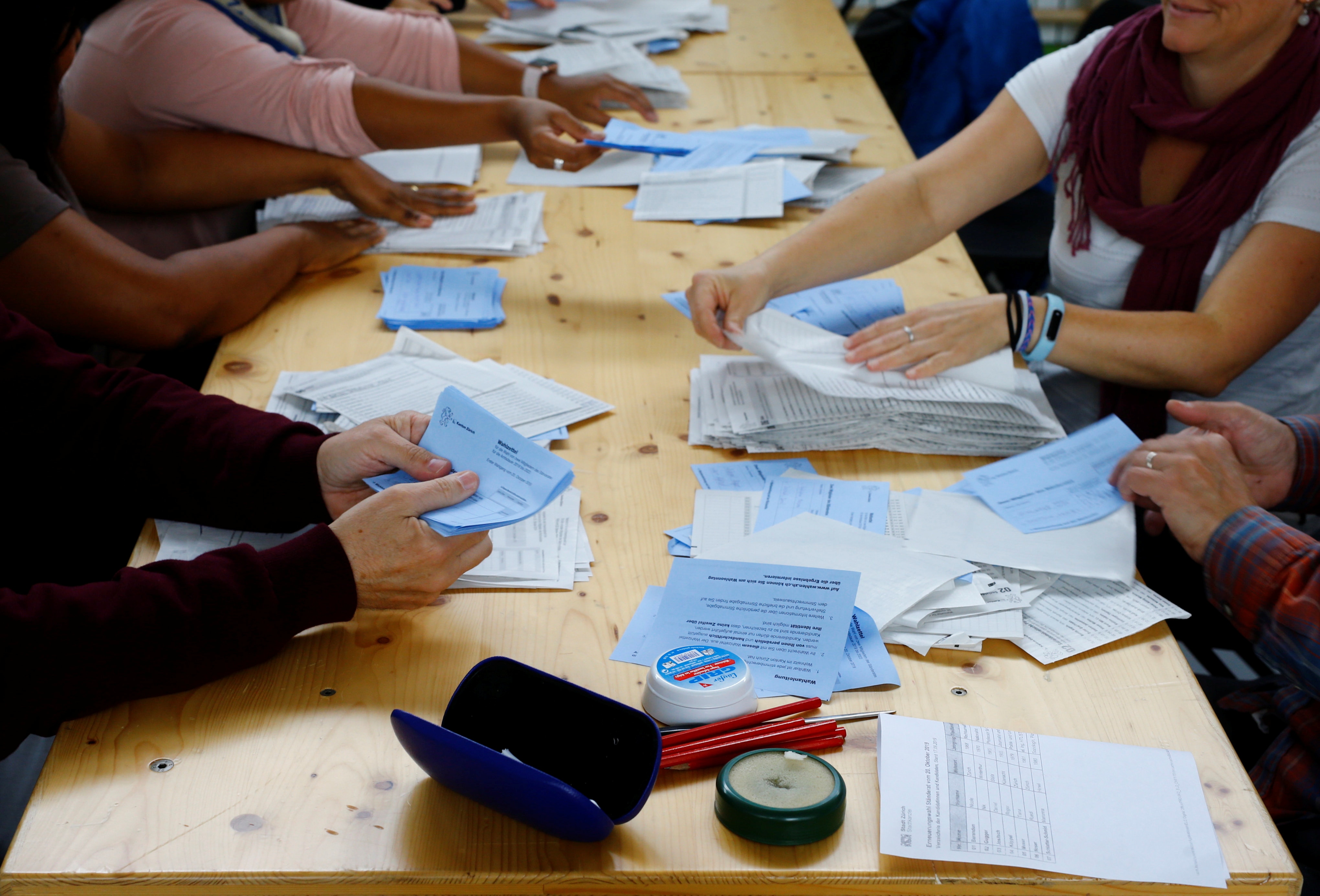 A close up of a table with members sorting out Swiss ballot papers.