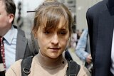 Close up of Allison Mack walking down the street looking down, surrounded by people