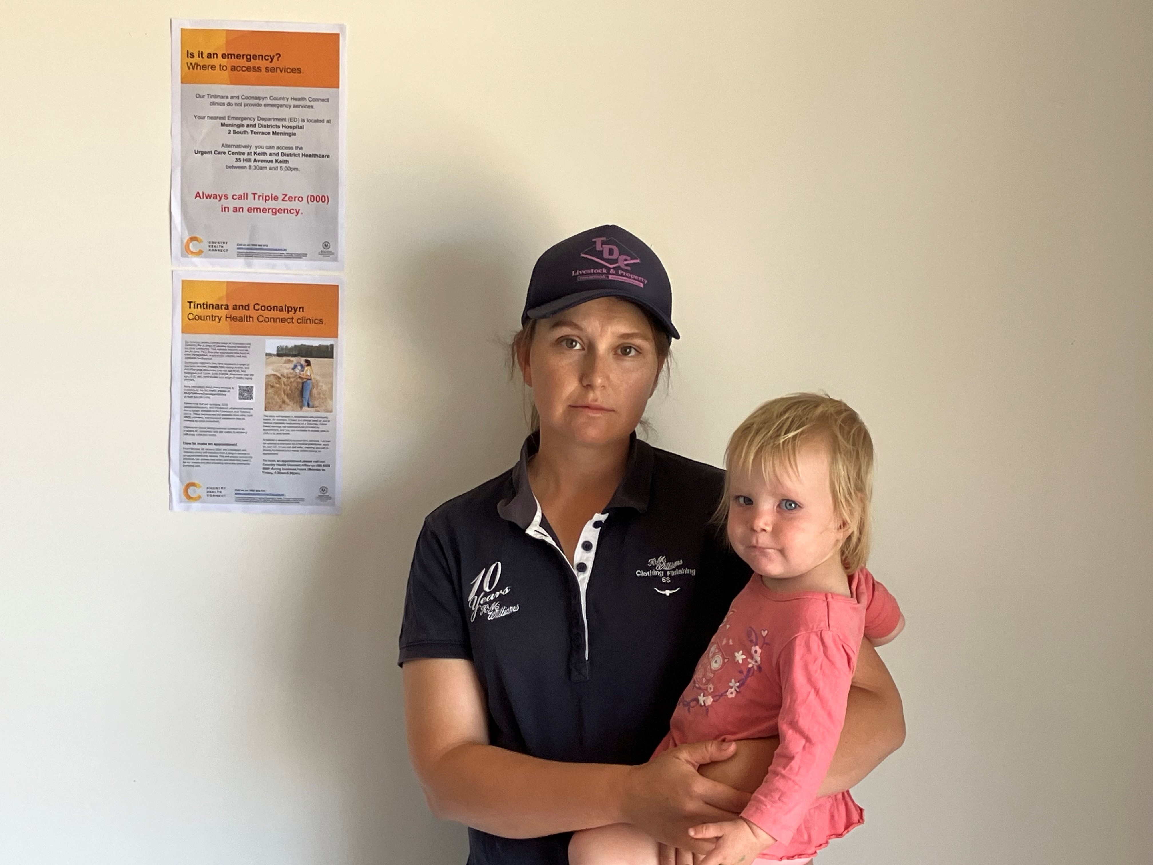 A woman wearing a black polo shirt and cap holding a baby