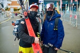 A man and a woman dressed in face masks and ski gear