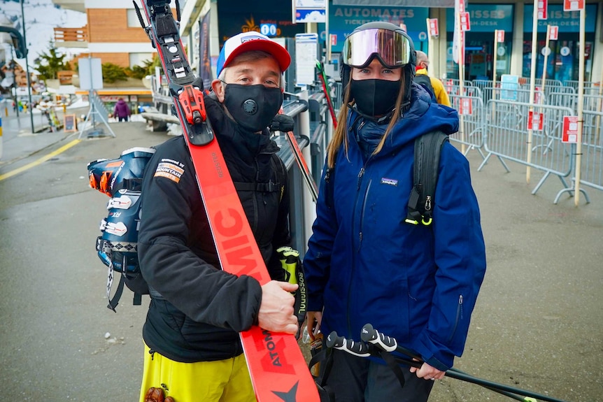 A man and a woman dressed in face masks and ski gear