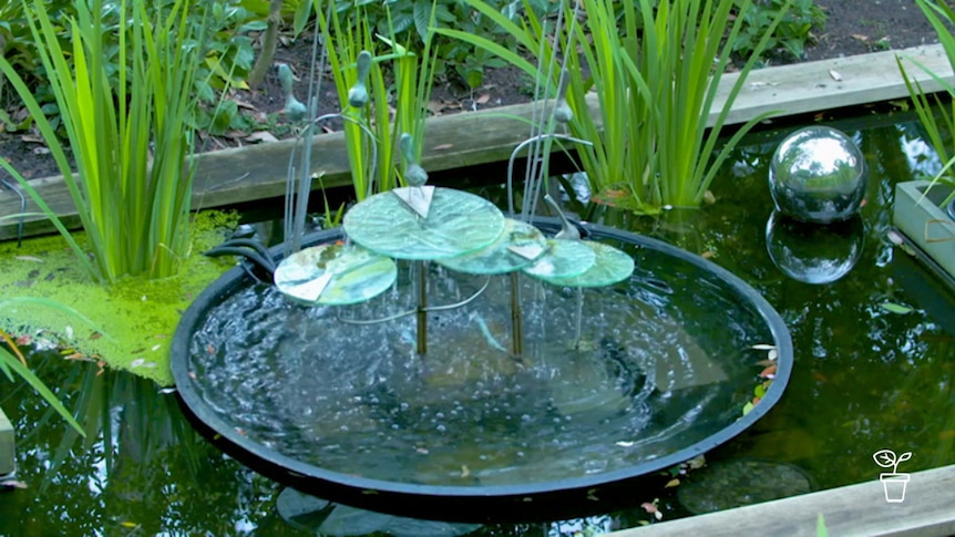 Water feature in garden with glass lily pads and silver floating ball