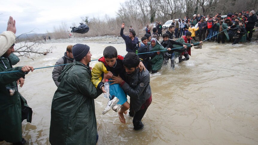 Asylum seekers wade across a river near the Greek-Macedonian border.