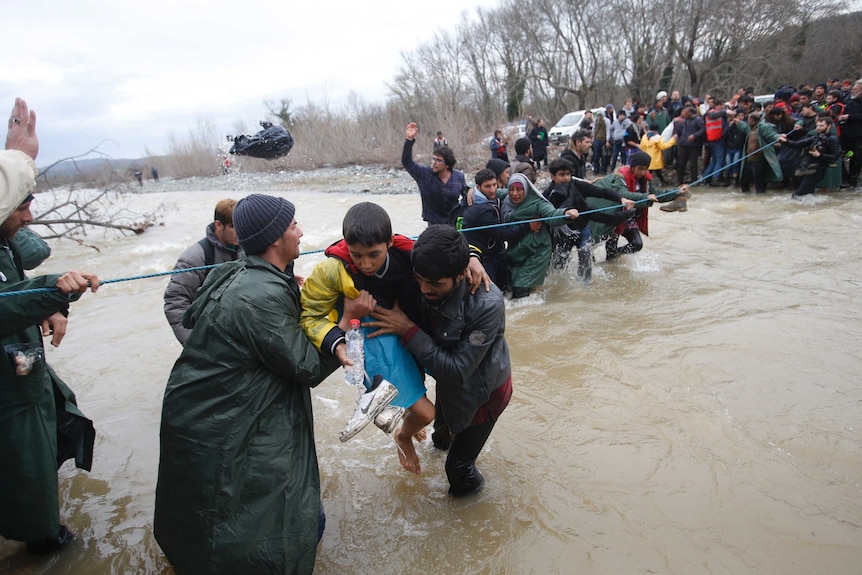 Asylum seekers wade across a river near the Greek-Macedonian border.