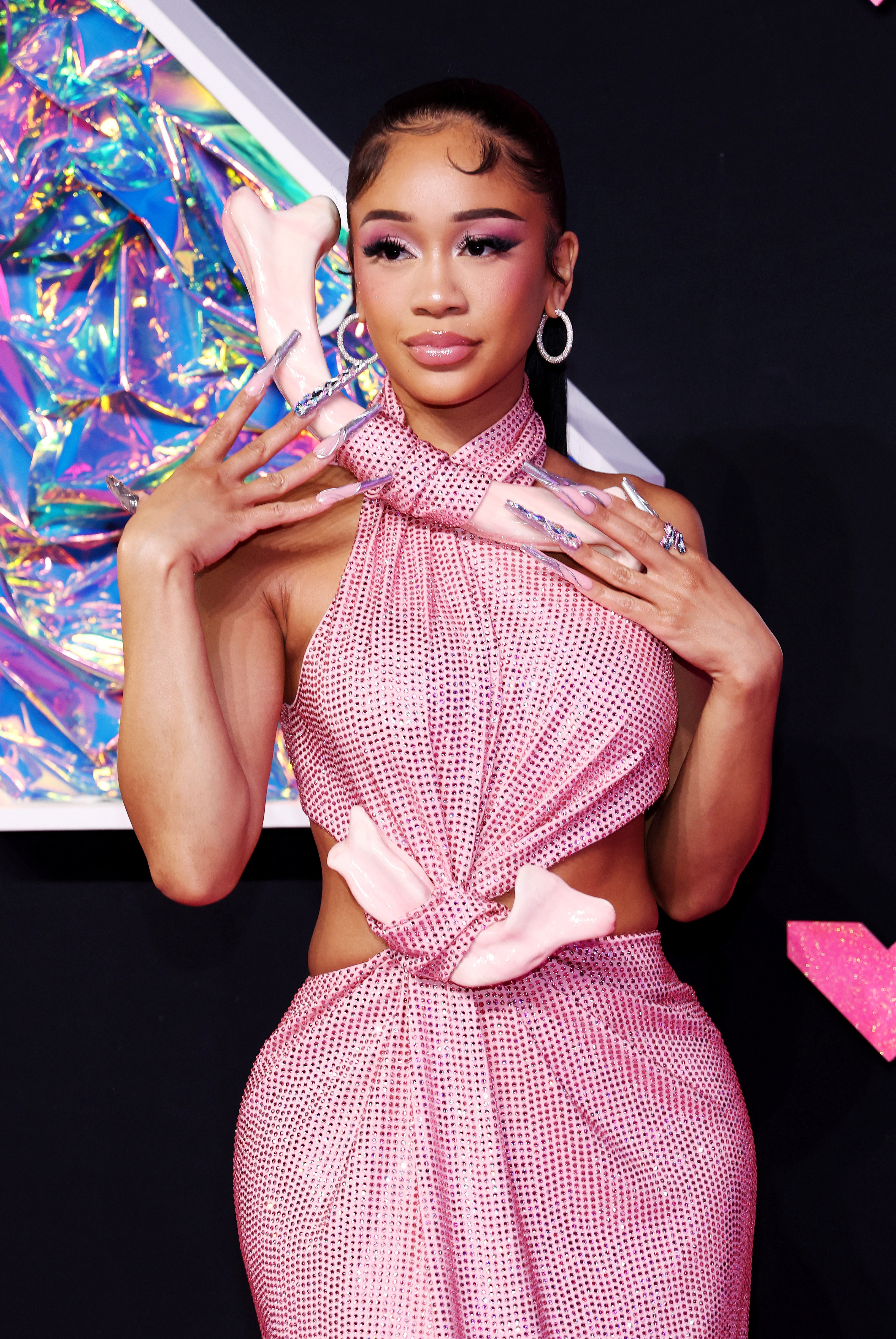 Saweetie is wearing a pink sparkly dress with pink bone-like accessories.