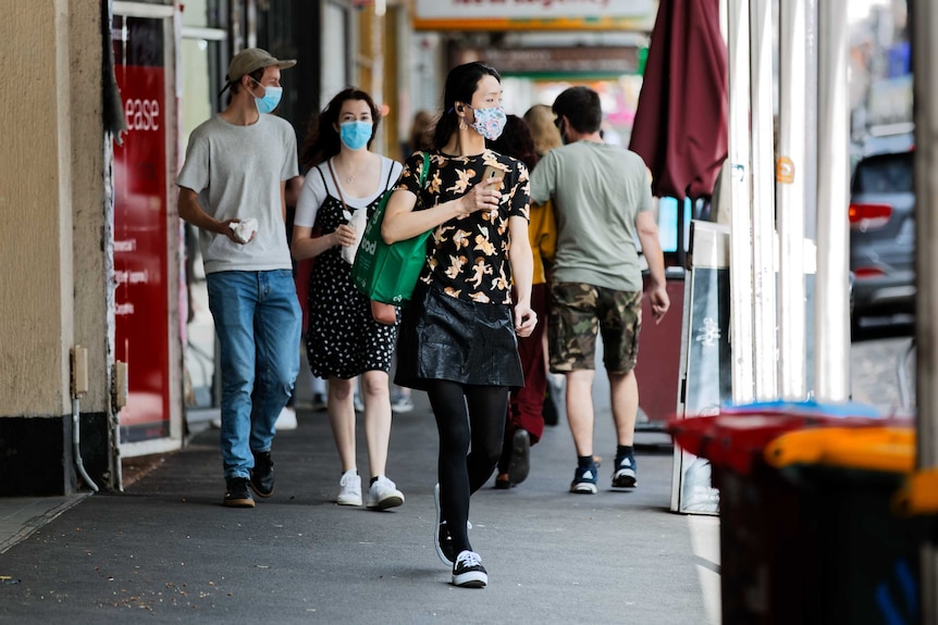 A photo of people wearing masks walking along a Melbourne footpath.