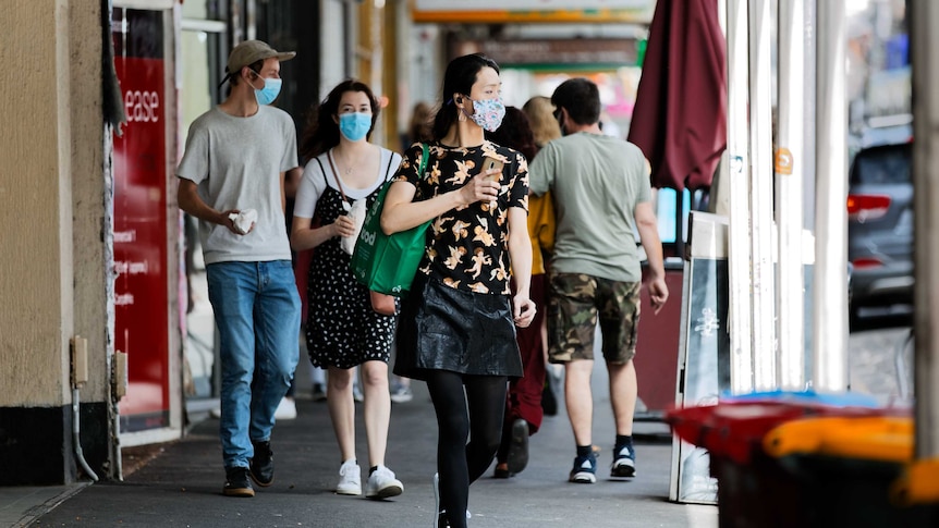 A photo of people wearing masks walking along a Melbourne footpath.