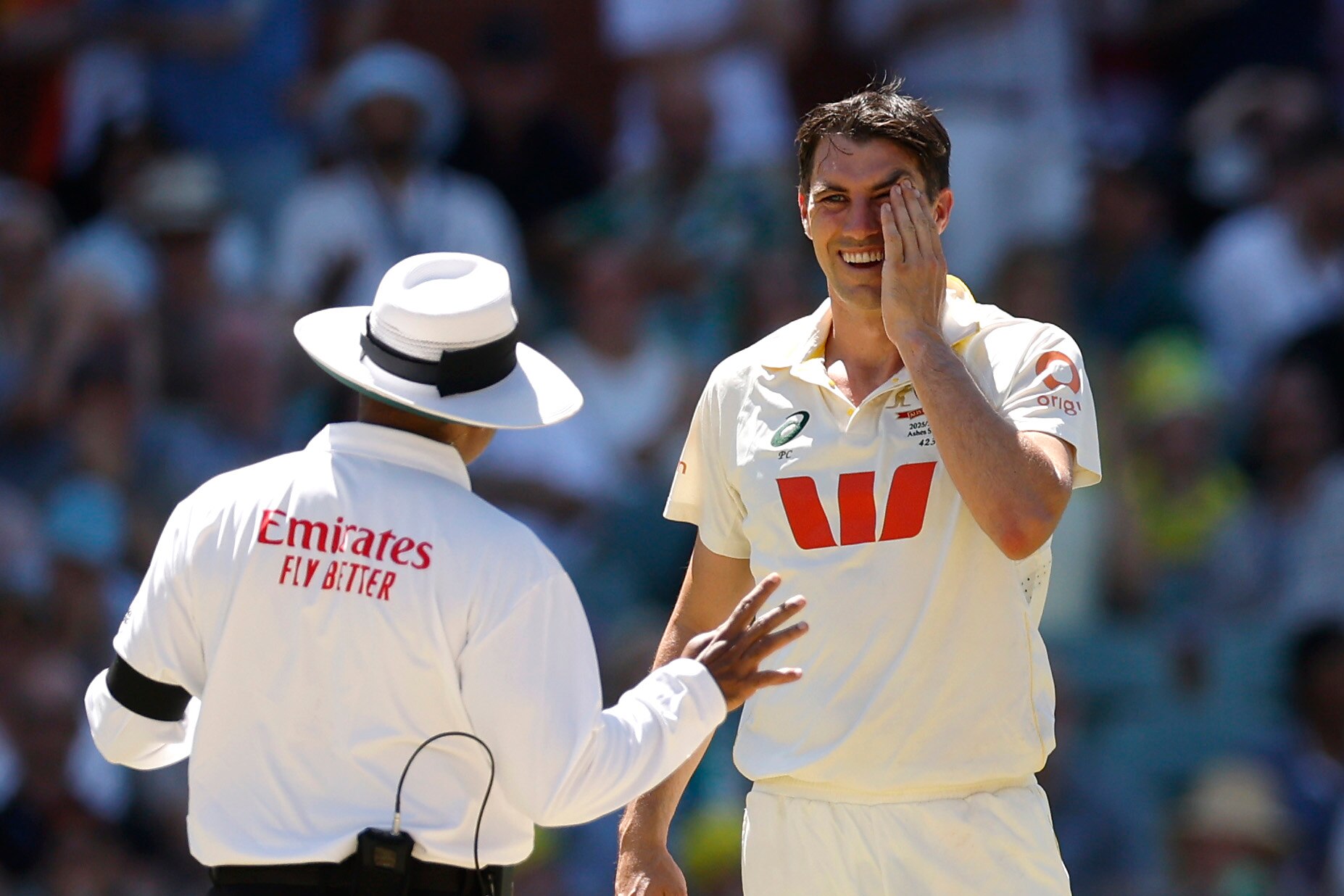 Pat Cummins holds his hand to his face as he speaks to an umpire