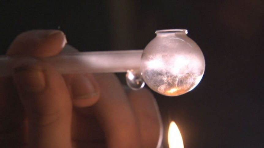 A close-up shot of a person smoking ice from a meth pipe.