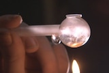 A close-up shot of a person smoking ice from a meth pipe.