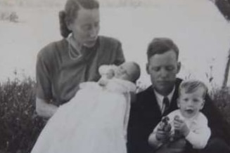 black and white family photo of baby in christening dress