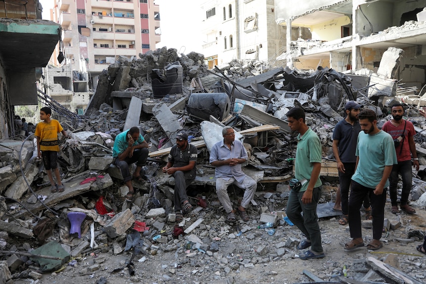 Men stand and look at the rubble after Israeli strikes in Gaza.