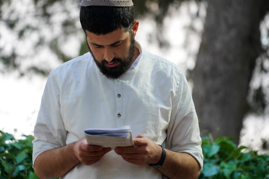 A man looking down, reading religious papers.