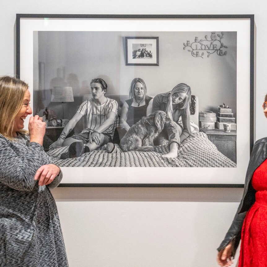 two women stand laughing in front of a portrait image