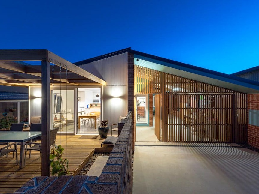 An image of the outside of a modern house with lots of windows.