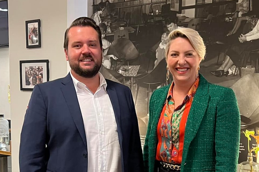 Man in suit stands next to woman in suit