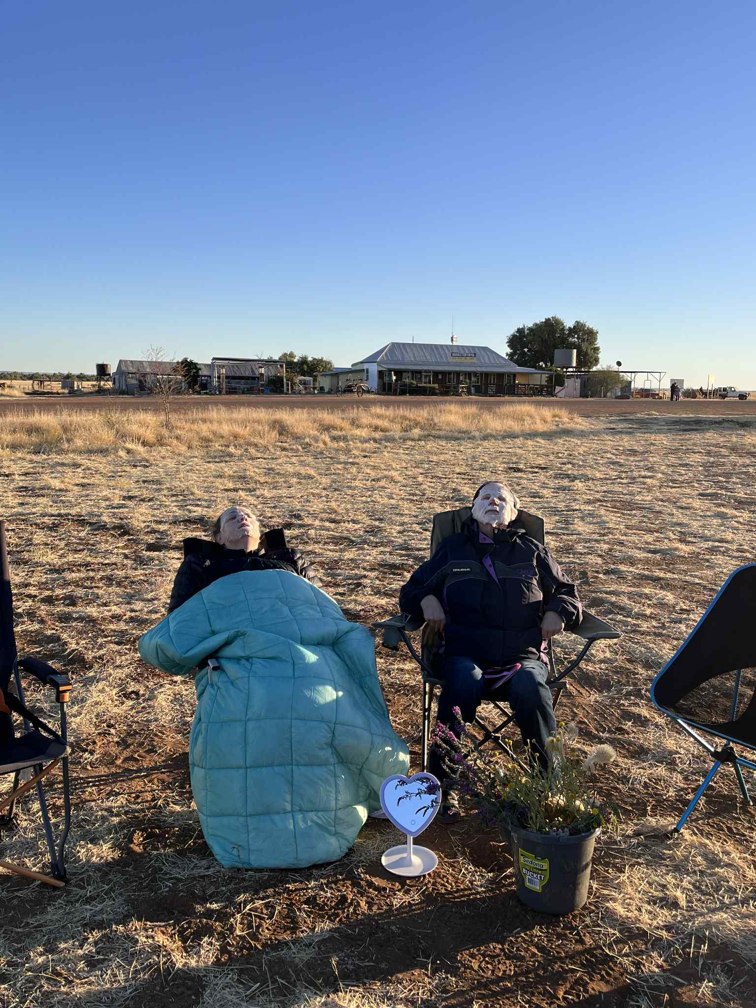 Dos mujeres se sientan en sillas de camping y se reclinan con máscaras faciales. 