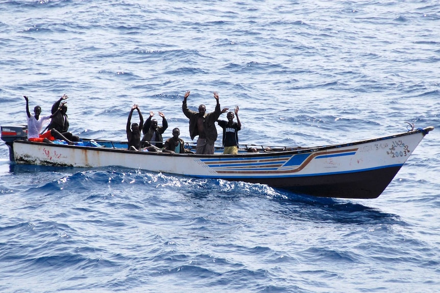 Suspected Somali pirates raise their hands in their skiff during their arrest.