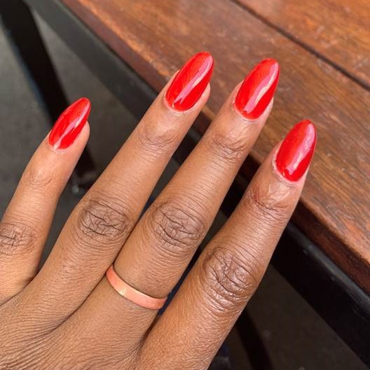 A hand showing off freshly painted, long red nails.