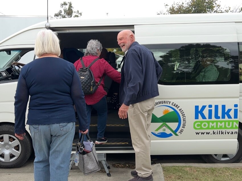 A group of elderly people hop into a mini-van with Kilki and community visible on it.