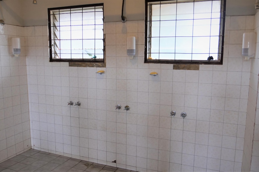 Old communal shower with no doors.