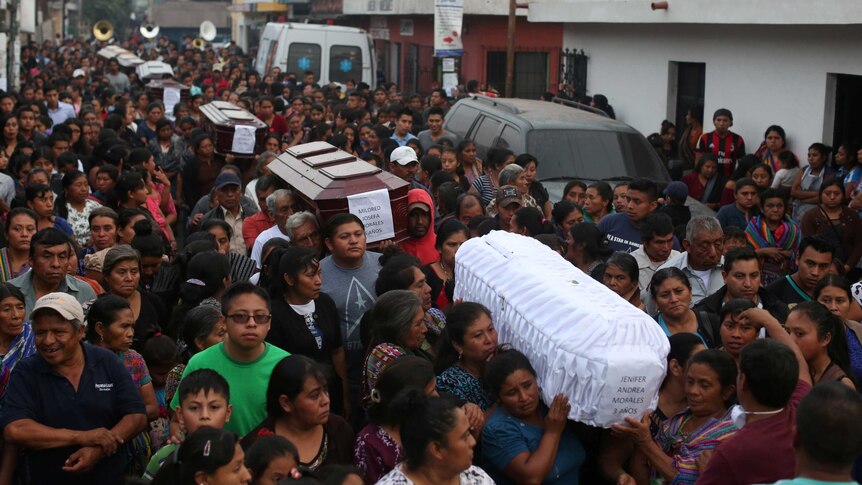 A crowd of people carry coffins of victims who died during the eruption of the Fuego volcano.