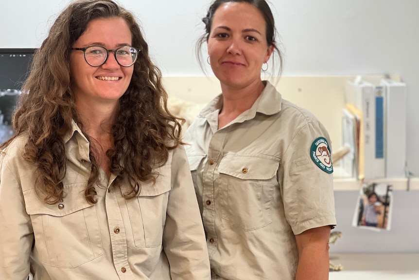 Two women in wildlife uniforms smiling at the camera from an office.