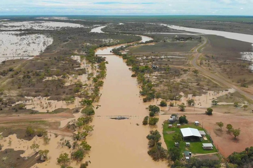 An outback river with it's banks broken and water flowing onto the flood plane