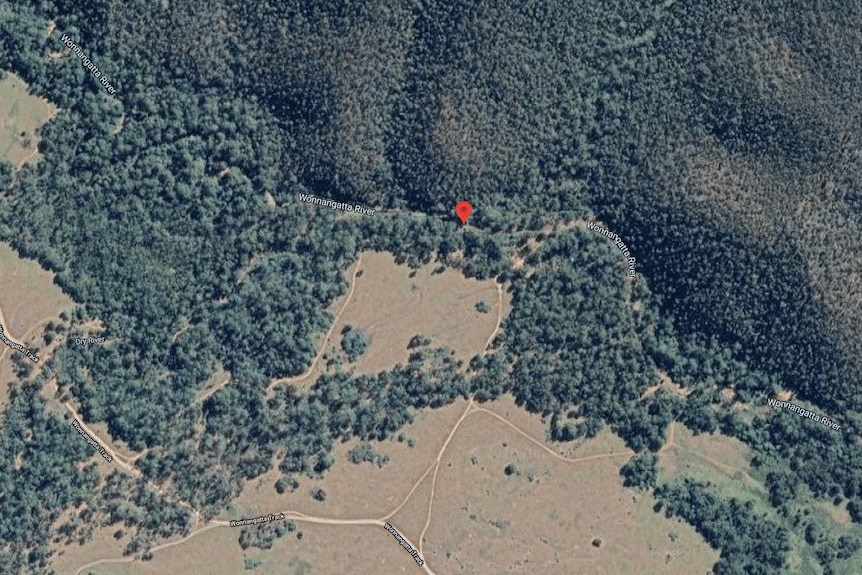 An aerial image showing dense bushland. A small red marker indicates a campsite.