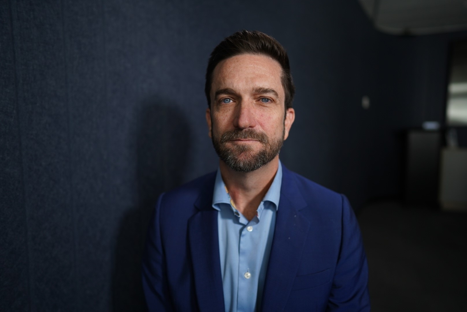 A man wearing a blue shirt under a blue jacket.