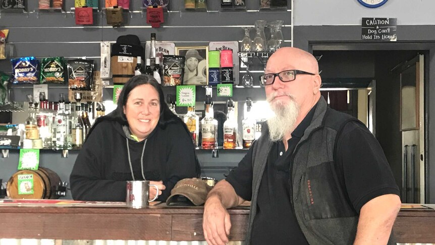 Lady behind the bar, man on stool in front of bar