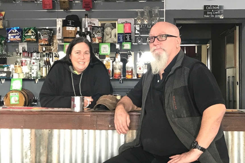 Lady behind the bar, man on stool in front of bar