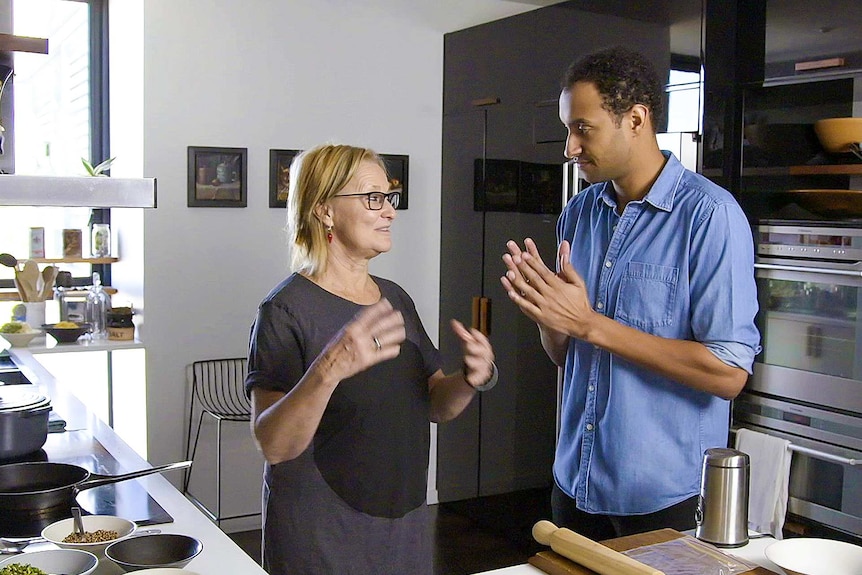 Australian chef Christine Manfield and Matt Okine in a kitchen about to make an Indian dahl recipe.