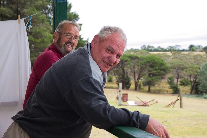 Two men relaxing on a balcony overlooking a rural view