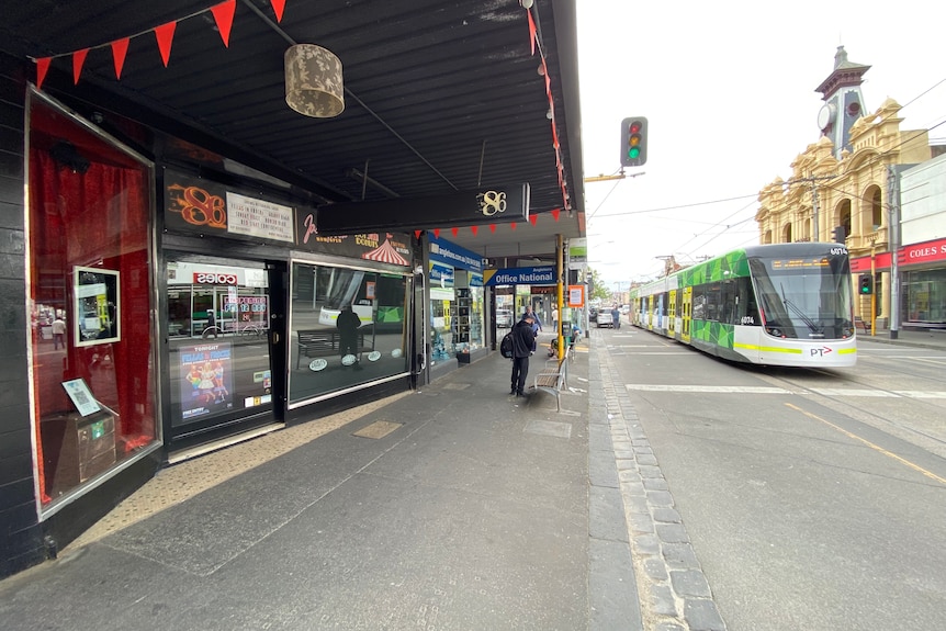 A tram goes down Smith Street outside The 86 bar under bright grey skies.