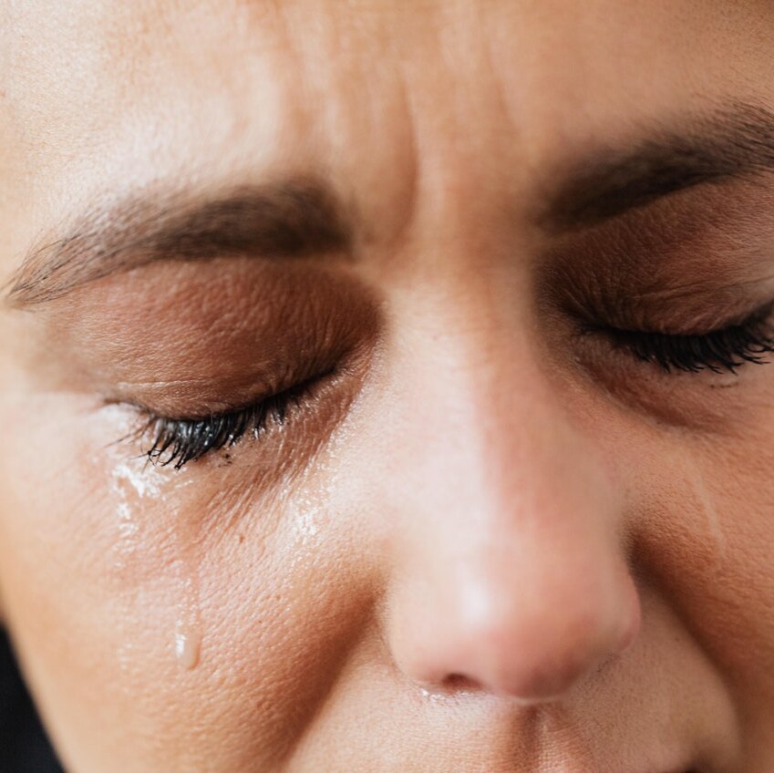 A woman cries and a tear runs down her face.