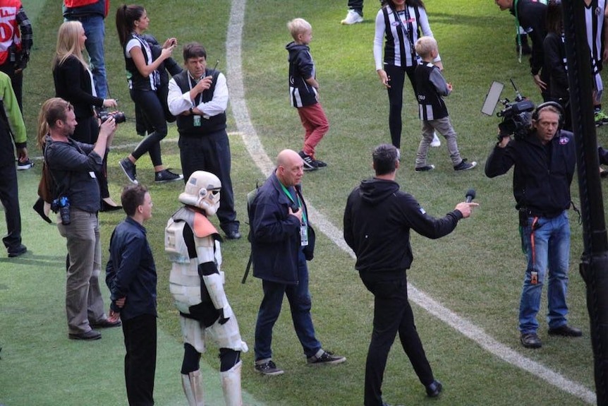 A man dressed as a star wars storm trooper on a football oval.