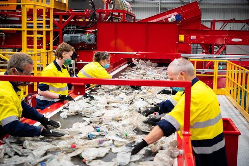 Four people in high-vis sort plastics on a production line.