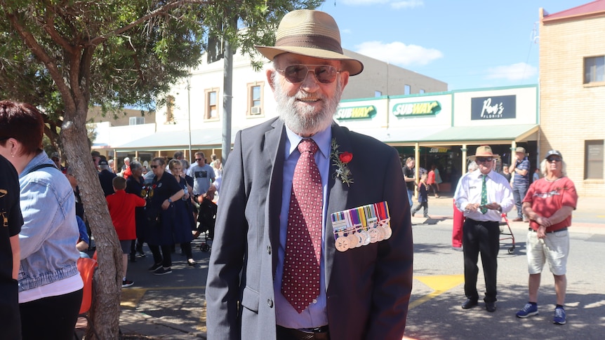 An older man in a hat with chest full of medals.