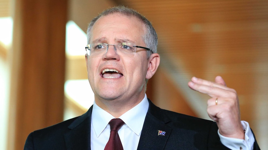 Scott Morrison gestures with his left hand and two fingers during a press conference
