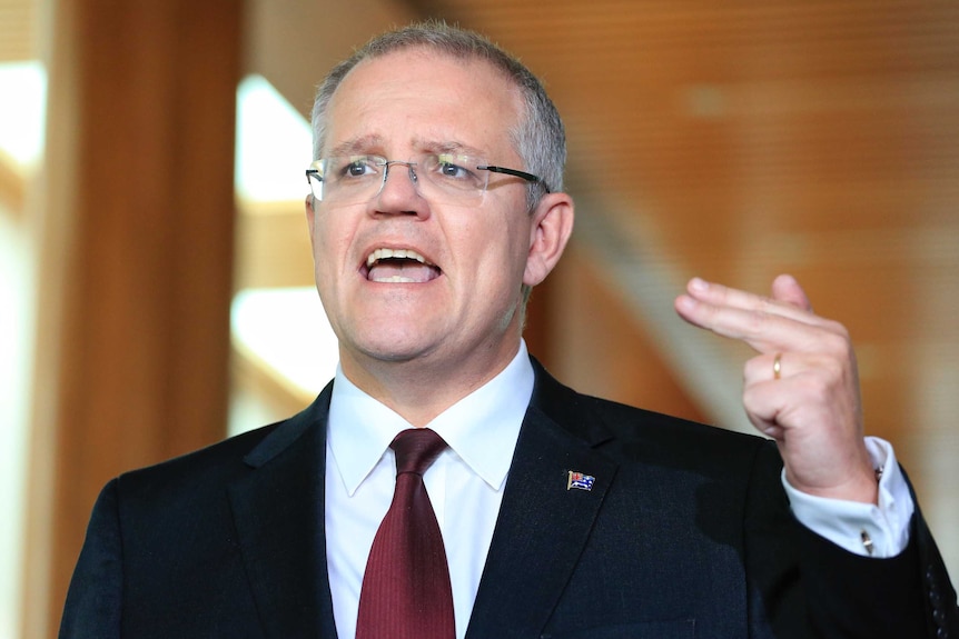 Scott Morrison gestures with his left hand and two fingers during a press conference