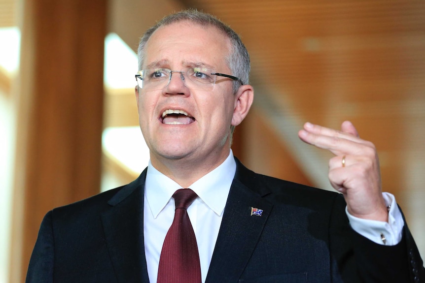 Scott Morrison gestures with his left hand and two fingers during a press conference