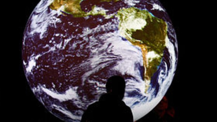 Picture of a man standing in front of an image of the earth in space (Getty Images)