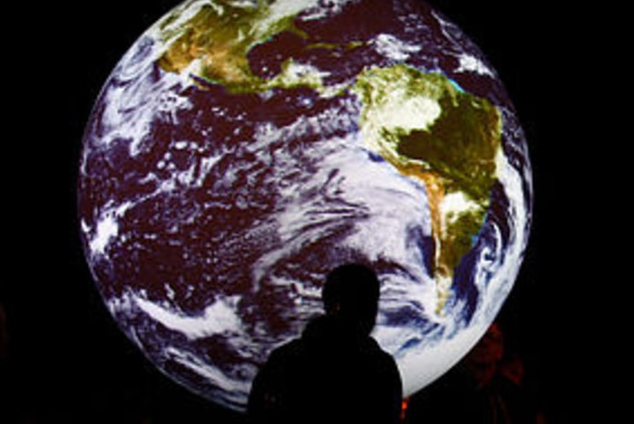 Picture of a man standing in front of an image of the earth in space (Getty Images)