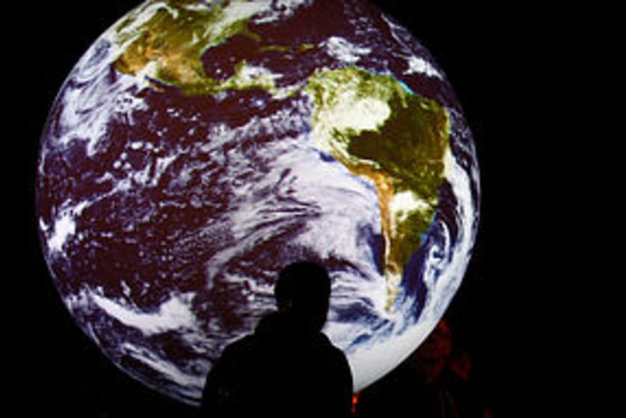 Creative: Man stands in front picture of Earth (Miguel Villagran, Getty)