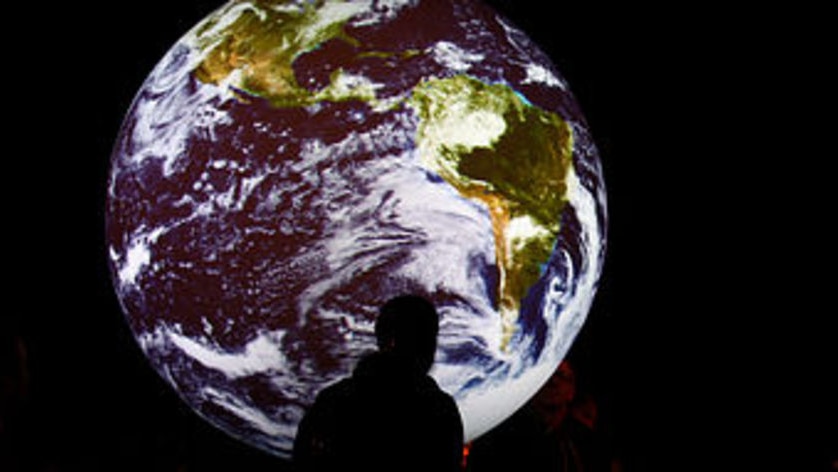 Creative: Man stands in front picture of Earth (Miguel Villagran, Getty)