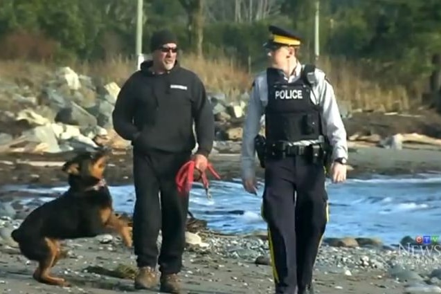 Mike Johns and his dog Taz walk along the beach with a police officer.