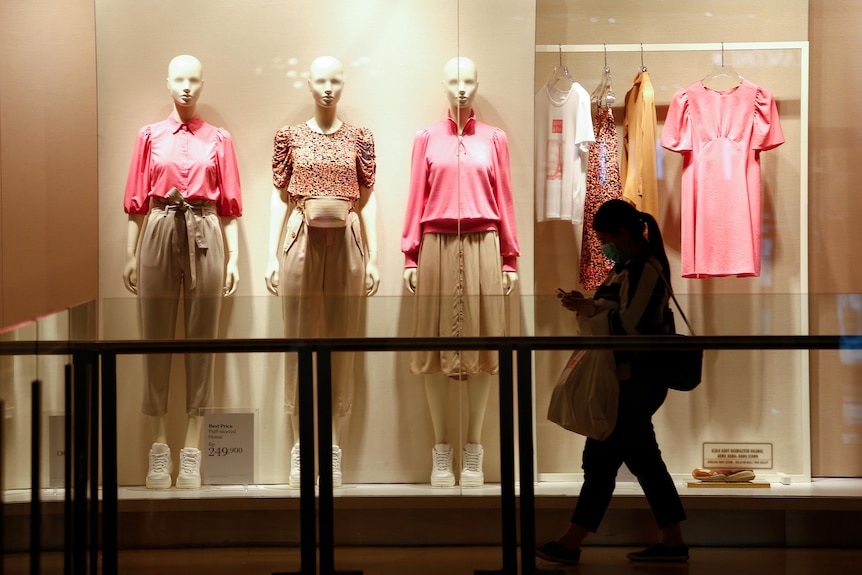 A shopper walks past mannequins in a mall.